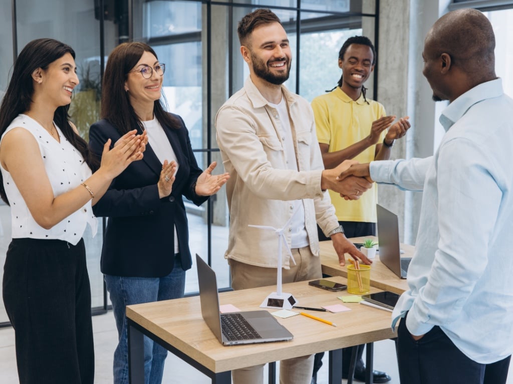 Equipo de colaboradores celebrando un logro en la oficina, ejemplo de qué es el salario emocional y cómo el reconocimiento fortalece el compromiso laboral.